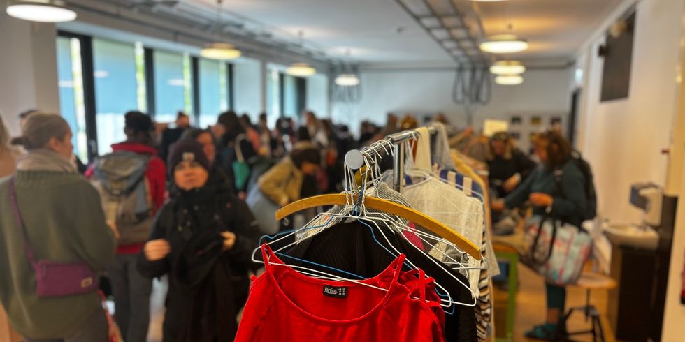 Kleiderständer im Werkraum der Bezirkszentralbibliothek Pablo Neruda mit Menschen unscharf im Hintergrund