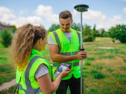 Zwei Vermessungstechniker vermessen ein Gelände