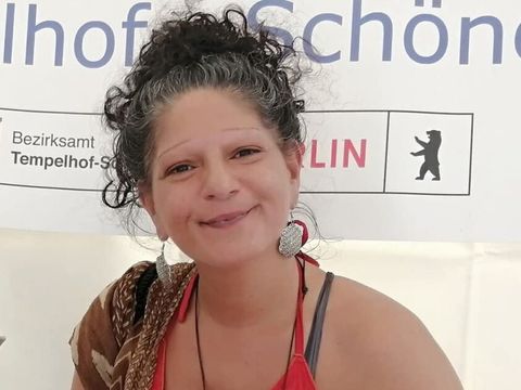 Eine Frau steht hinter einem Stand und lächelt in die Kamera.