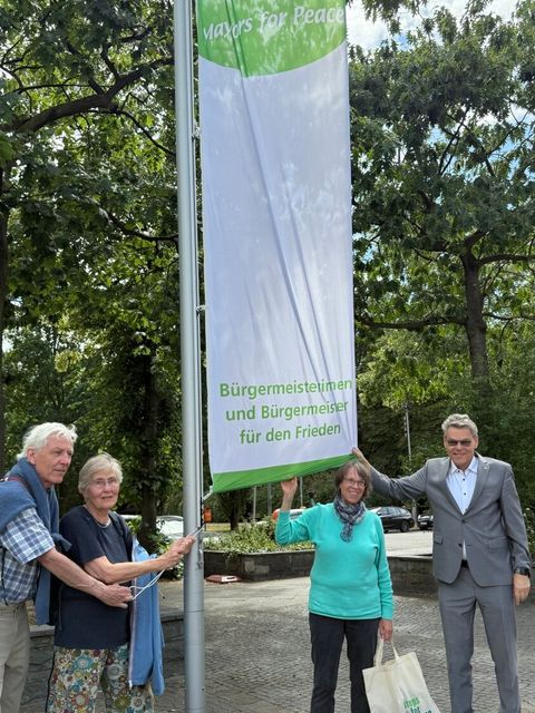 Bezirksbürgermeister Jörn Oltmann mit den Vertreter_innen von Friedensorganisationen beim Hissen der Mayors for Peace-Flagge.