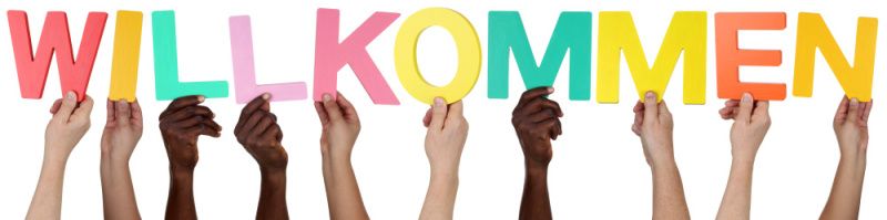 Hände aus verschienen Nationen halten das Wort Willkommen hoch