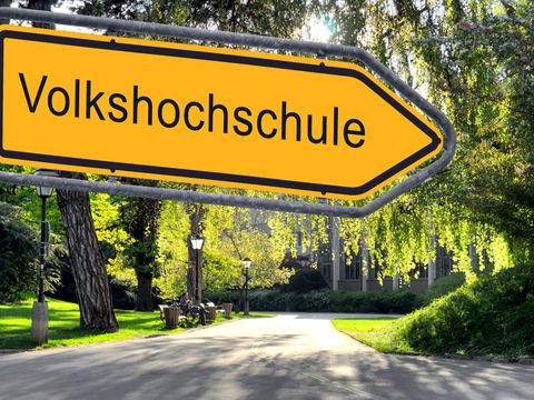 Gelbes Ortsnamenschild mit der Aufschrift Volkshochschule