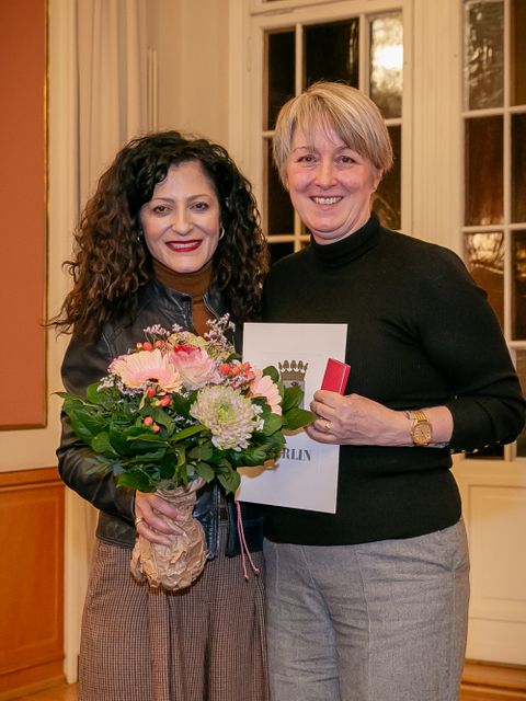Cansel Kiziltepe, Senatorin für Arbeit, Soziales, Gleichstellung, Integration, Vielfalt und Antidiskriminierung, überreicht die Ehrennadel.