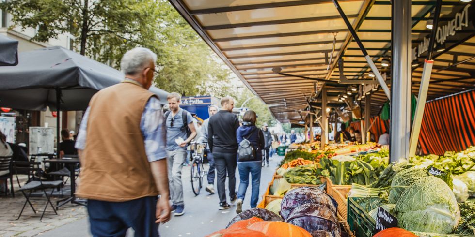 Impression vom Boxhagener Wochenmarkt, im Vordergrund ist ein Kürbis zu sehen im hintergrund einkaufende Menschen und Stände