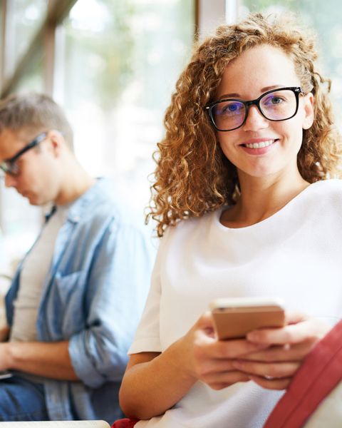 Ein Portrait einer jungen Frau mit Mobiltelefon in der Hand