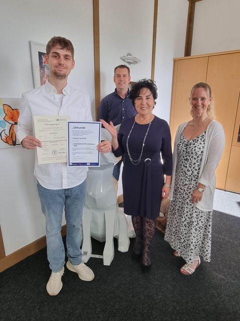Pascal Schmidt (li.) freut sich über die Anerkennung als Jahrgangsbester und die Glückwünsche von Bezirksbürgermeisterin Emine Demirbüken-Wegner (2.v.l.). Außerdem auf dem Bild: Ausbildungsleiterin Alexandra Bansemer sowie Ausbilder Andreas Kattner. (Bild: BA Rdf)