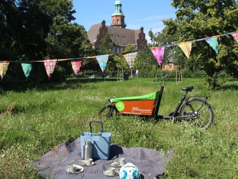 Ausgepackter Kiez-Korb auf einer Wiese im Park mit Lastenrad im Hintergrund