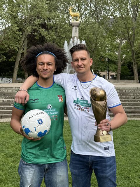 Zwei Mitarbeitende des Ehrenamtsbüros präsentieren den Pokal und die Trikots.