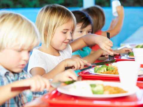 Grundschüler sitzen an einem Tisch und essen gemeinsam Mittag