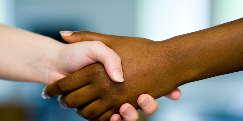 Schwarze und weiße Hand fassen sich an