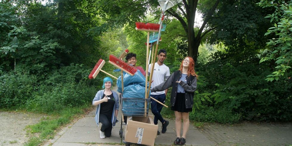 "Kehrenbuerger" des PULS-Camps - Junge Menschen mit vielen Besen, einem Einkaufwagen und zwei randvollen blauen Müllsäcken