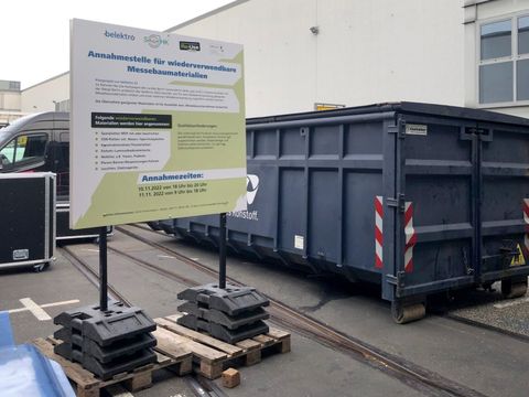 Bauschuttcontainer und Informationstafel zur Annahmestelle für Messematerialien