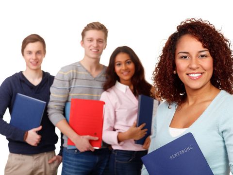 Zwei junge Frauen und zwei junge Männer, lächelnd, mit jeweils einer Bewerbungsmappe in der Hand