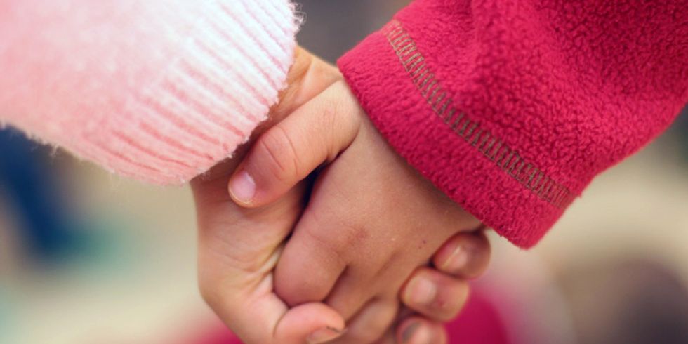 Zwei Kinderhände halten einander