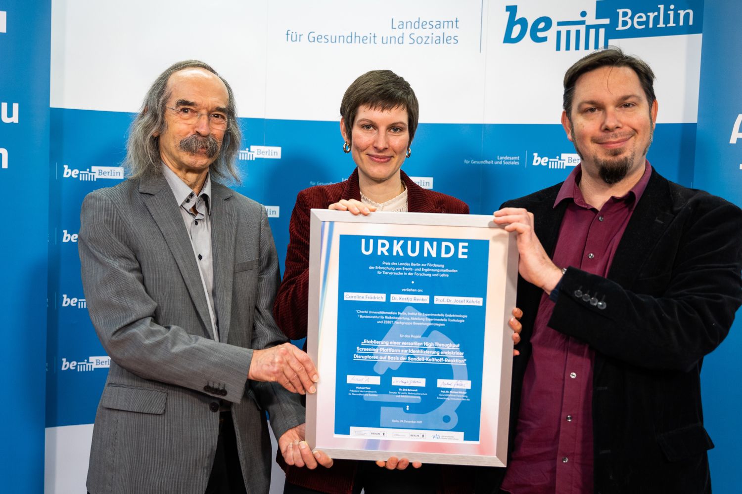Die drei Preiträger halten Urkunde vor die Kamera