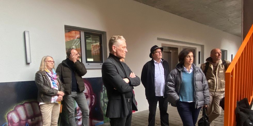Der stellvertretende Bezirksbürgermeister, Oliver Nöll, und weitere Personen vor der Gedenktafel in der ehemaligen Gerhard-Hauptmann-Schule