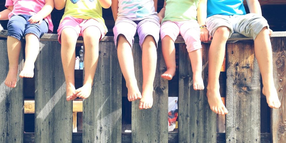 Kinderbeine bäumeln über einem Zaun