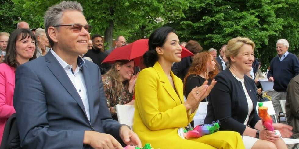 Mehrere Personen sitzen in Reihen und lächeln und applaudieren.