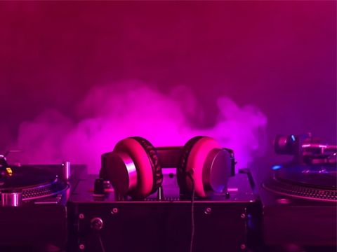 in einem pinken Licht liegen Kopfhörer auf einer Soundanlage