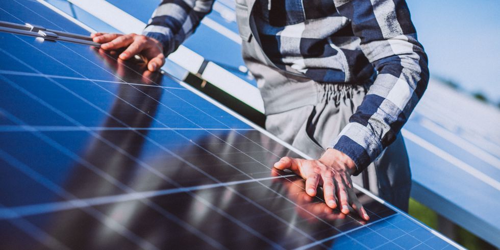 Das BIld zeigt einen Mann, der ein PV-Modul installiert.