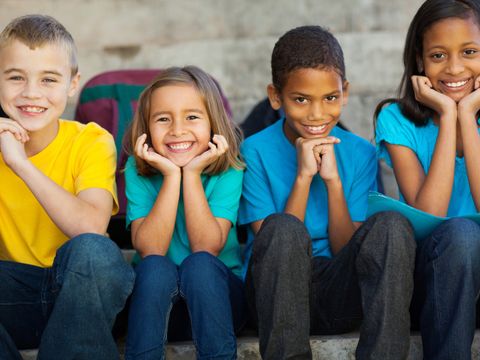 Vier Kinder sitzen auf einer Bank und stützen die Köpfe auf Ihren Händen ab