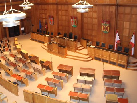 Ein großer holzgetäfelter Saal mt vielen Stühlen