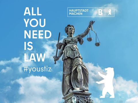 In der Mitte ist die Justitia zu sehen, links der Slogan "All You Need Is Law", rechts der Berliner Bär in weiß, der Hintergrund ist hel