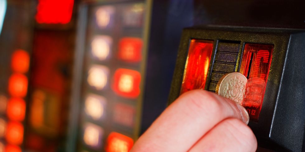 Eine Person wirft eine Münze in einen Spielautomat