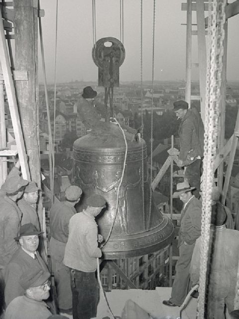 Handwerker arbeiten in einem Turm an einer großen Glocke