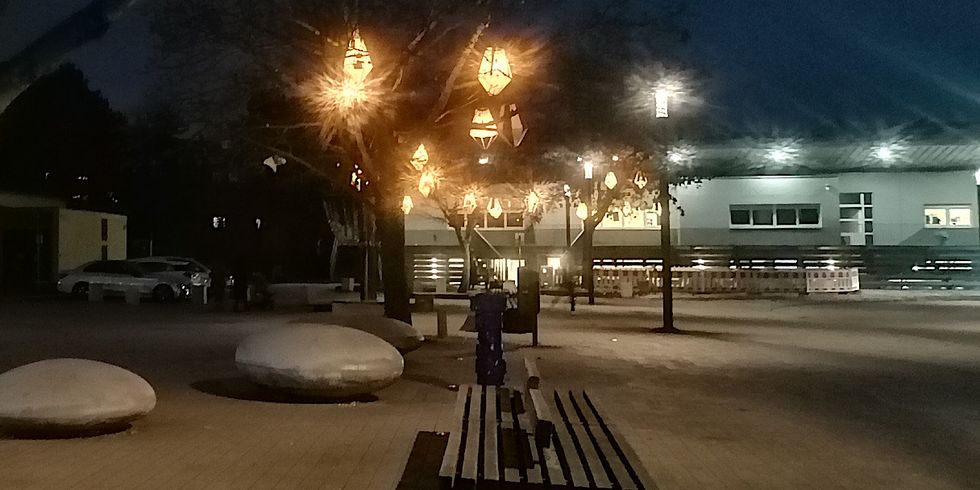 Quartiersplatz Westerwaldstraße - Klubhaus und Laternen des QM leuchten im Dunklen