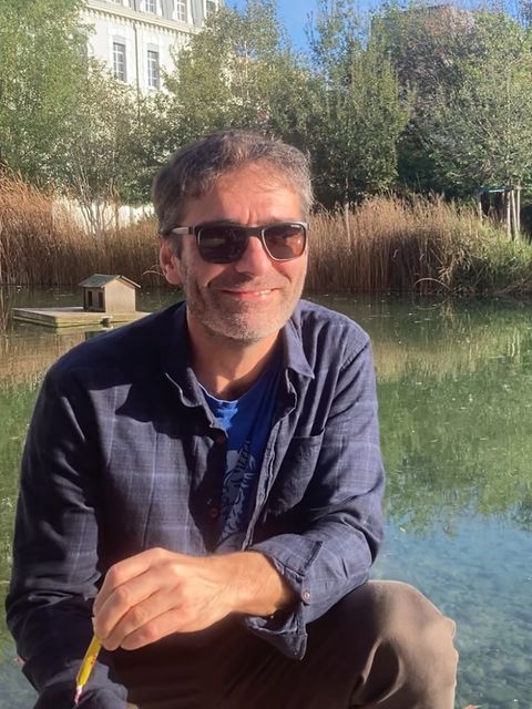 Kursleiter Floran Bayle mit Sonnenbrille in Frankreich mit Teich Schilf und Gutshaus im Hintergrund