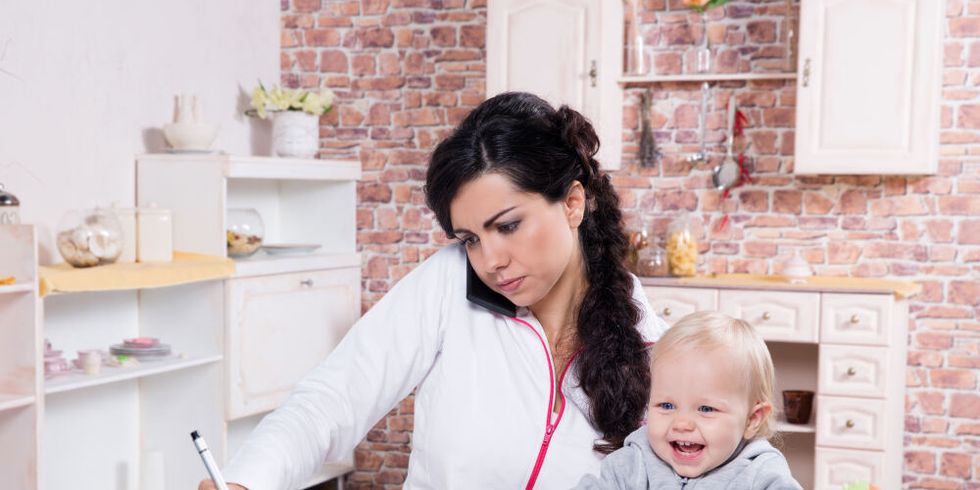 Mutter mit Kleinkind am Schreibtisch bei der Arbeit zu Hause