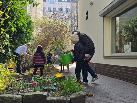 Kinder in einem Blumenbeet mit Gießkanne