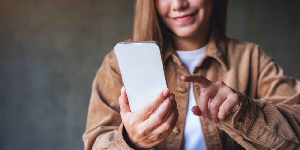 Eine Frau schaut lächelnd auf ihr Handy.