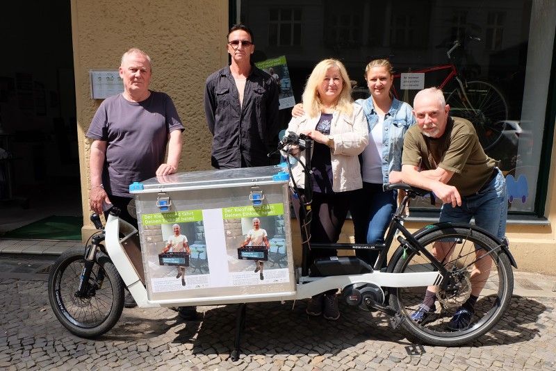 Das Team des Kiezfreundes im Klausenerplatzkiez hinter einem Transportrad stehend