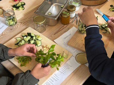 Kinderhände, die auf einem Holztisch Gemüse schneiden