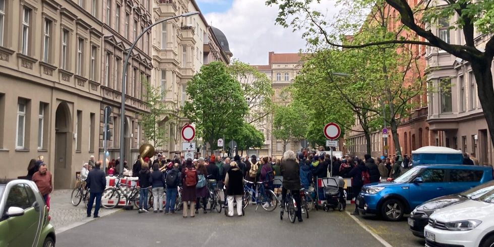 Eine Abschnitt einer Straße ist abgesperrt. Im abgesperrten Bereich sind viele Menschen versammelt.