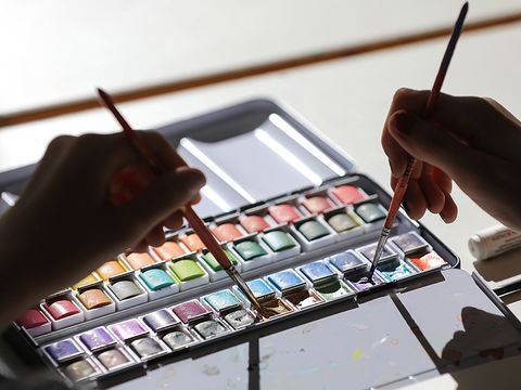 Malerei I: Kinder mischen mit einem Pinsel die Farbe im Aquarellkasten an. (Bild: © Sebastian Runge)