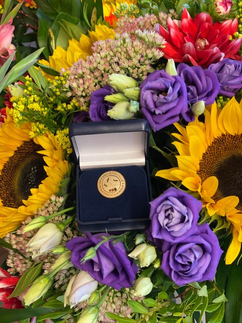 Bürgermedaille liegt auf einem bunten Blumenstrauß