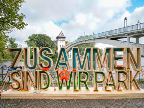 Schriftzug "Zusammen sind wir Park" mit Aufräumequipment
