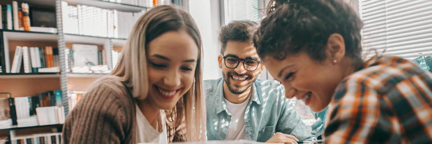 Eine Gruppe Studierender schaut auf ein Tablet und lacht