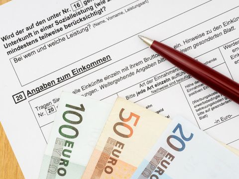 Geldscheine und ein Stift liegen auf einem Wohngeldantrag
