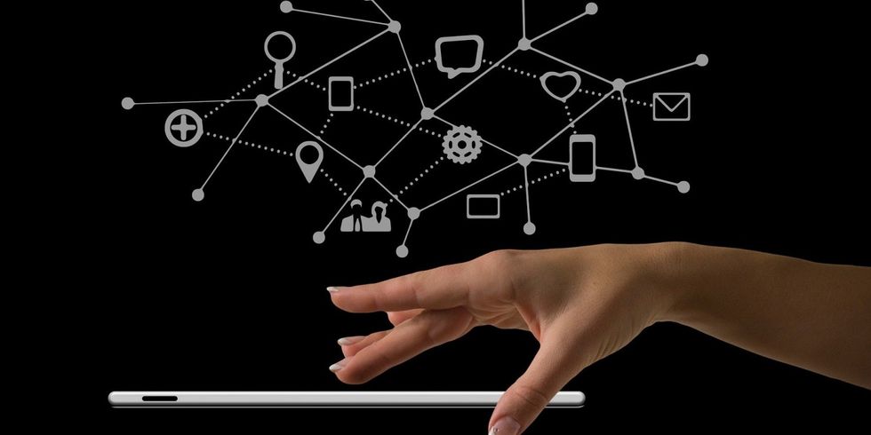 Hand bedient mobiles Gerät, darüber Zeichen von vernetzten Symbolen