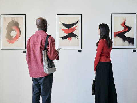 Ein Mann und eine Frau schauen sich Bilder bei einer Ausstellung an