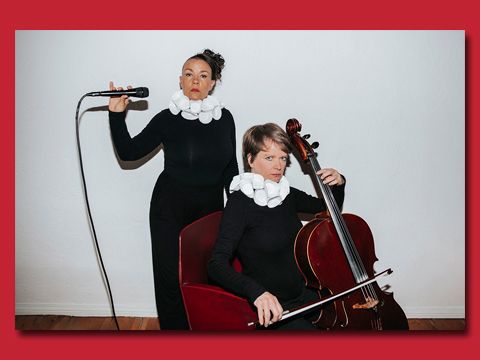 eine stehende Frau mit einem Mikrophon, davor eine sitzende Frau mit einem Cello