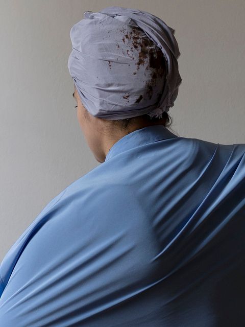 eine Frau von hinten in blauem Umhang und mit Kopftuch