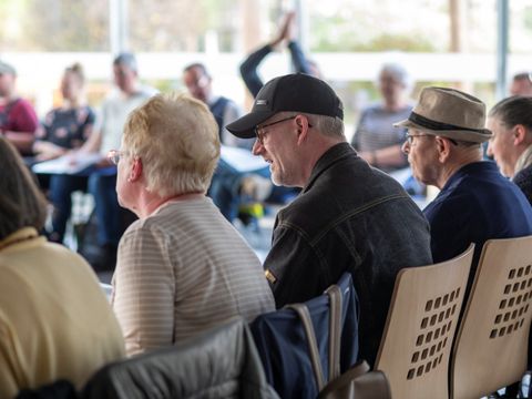 Bild von sitzenden Menschen in einem Stuhlkreis, die gemeinsam singen