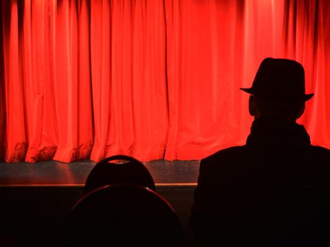 Mann_sitzt_vor_rotem_Vorhang