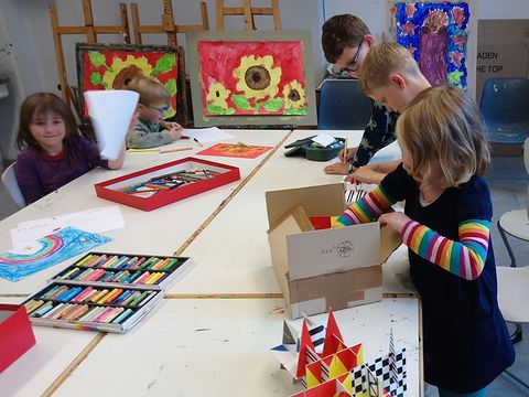 Rot. Gelb. Blau. Wir malen!: Kinder arbeiten am Tisch mit Bildern auf Staffeleien im Hintergrund. (Bild: © Jugendkunstschule Pankow)