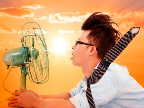 ein junger Mann kült sich vor einem Ventilator ab